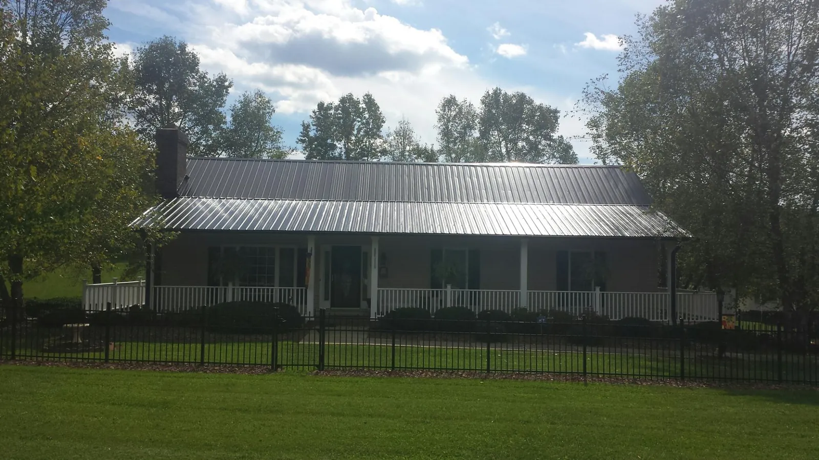 Gray metal roof on a brick ranch with a full width front porch — Gutter Guard Installation work by our crew in Amherst