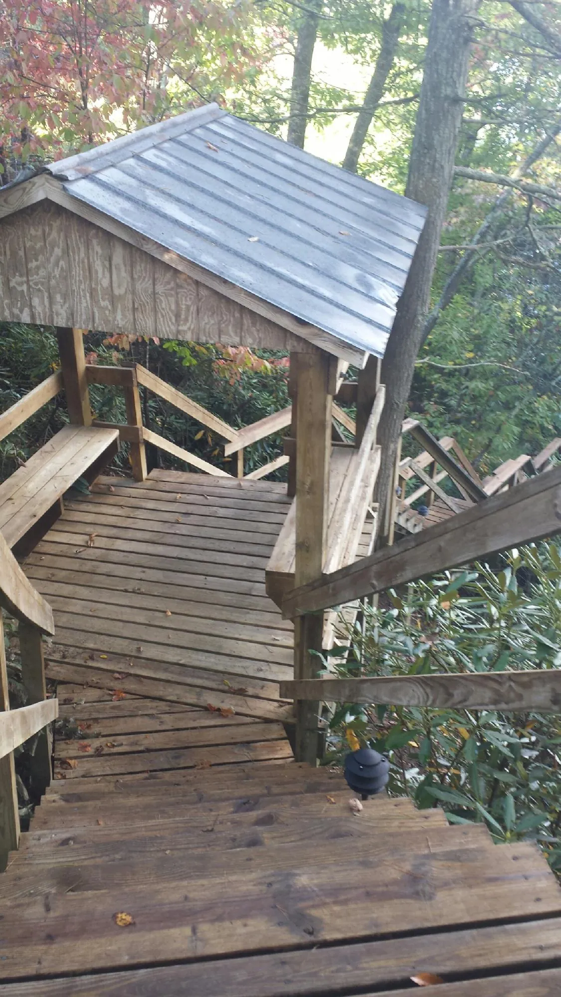 Metal roofed shelter over wooden steps on a wooded walkway — Skylight Repair & Installation work by our crew in Amherst